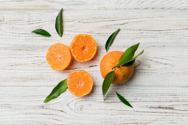 许多新鲜成熟的柑橘与绿色叶子彩色背景，俯视图，文本空间图片下载