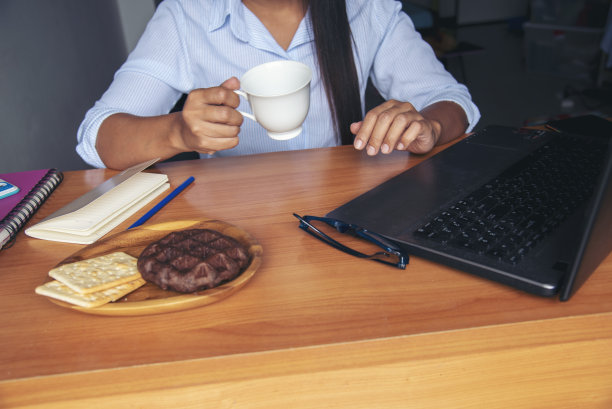 亚洲女性自由职业者使用笔记本电脑在家庭办公室办公桌。计划分析市场数据。亚洲女性工作的办公室与商务的东西，咖啡杯图片下载