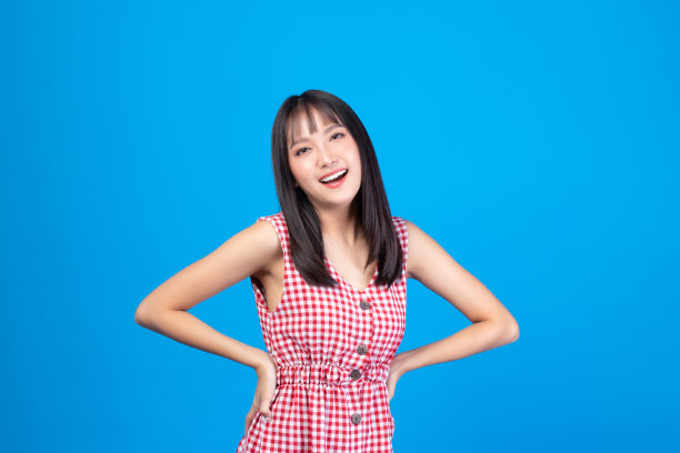 美丽的年轻亚洲女孩模特的肖像长发在随意的夏装微笑，快乐和享受在工作室孤立的蓝色背景。图片下载