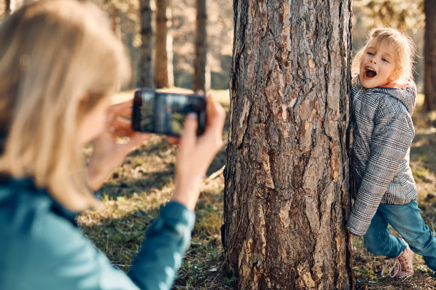 快乐的小女孩玩得很开心，妈妈在公园里给她拍照。图片下载