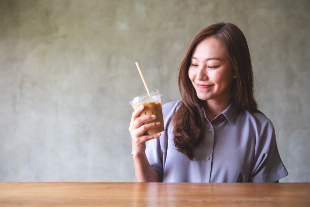 一个美丽的年轻亚洲妇女的肖像和喝冰咖啡图片下载