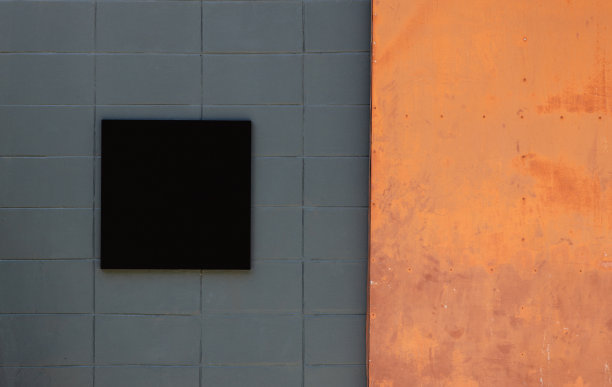 空白招牌上的黑色复印空间。它可以用于商店标志、餐厅、办公室等的模型，包括用于广告媒体。右边有一扇生锈的橙色铁门。图片下载