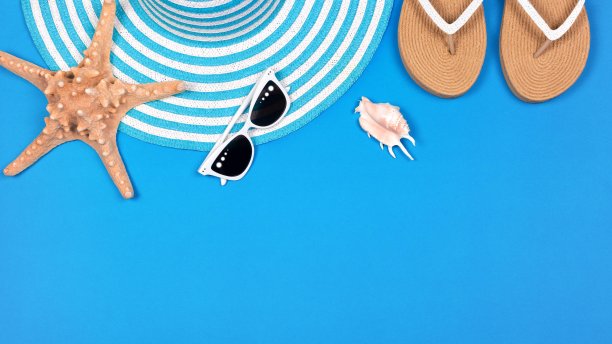 海滩设置平坦。条纹太阳帽，女性凉鞋，白色太阳镜和海星在蓝色背景，复制空间。图片下载