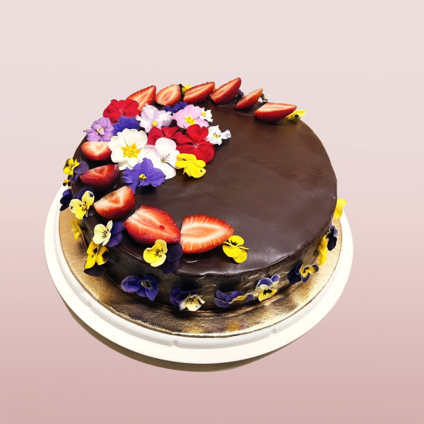 巧克力蛋糕由蔬菜原料制成，用浆果和鲜花装饰。蛋糕为素食者。素食者的美味甜点图片下载