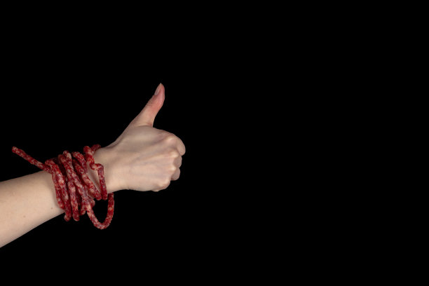用烟熏啤酒香肠做成手环，在黑色的背景上竖起大拇指图片下载