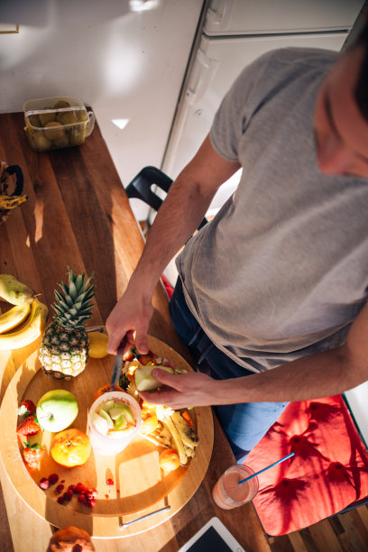 20多岁的素食主义者早上一边看平板电脑上的食谱，一边准备奶昔。图片下载