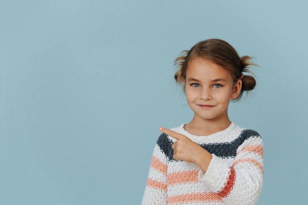 穿着条纹毛衣的小女孩咧着嘴用食指指着一边图片下载
