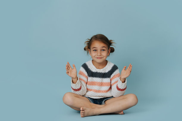 穿着条纹毛衣的可爱小女孩坐在地板上拍手图片下载