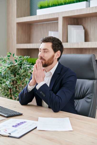 年轻的商人在桌前做瑜伽，祈祷，冥想，放松。无压力的工作，练习的时间，专注和幸福，保持健康的身体，心理和情绪水平的概念图片下载