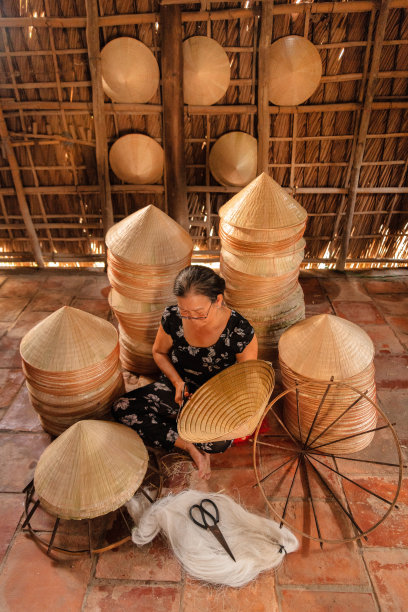 越南老妇人正在家中制作一顶传统的圆锥形帽子图片下载