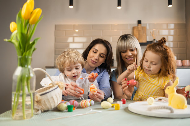 两位母亲和她的孩子用颜料装饰复活节彩蛋图片下载