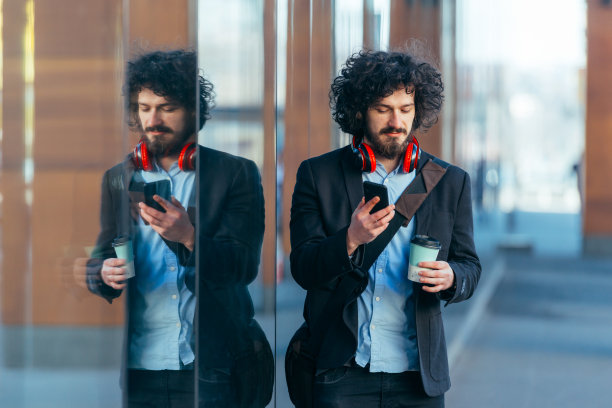 一个留着非洲式发型的快乐学生，背着男包，戴着耳机走在校园里。图片下载