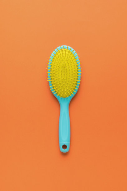 明亮的黄蓝色梳子在明亮的橙色背景上。图片下载