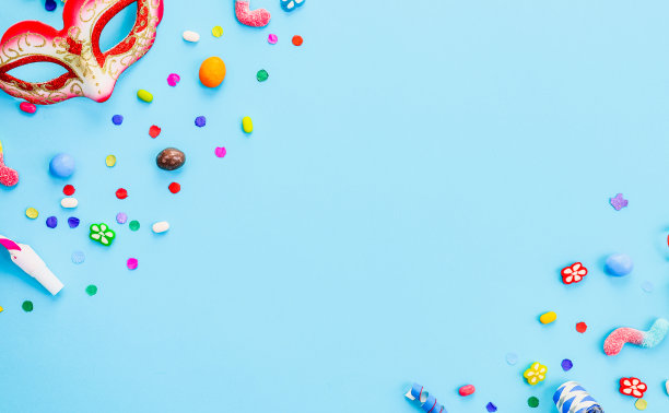 化妆面具，彩色纸屑，哨子，烟斗和软糖放在浅蓝色的两侧图片下载