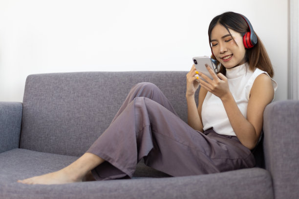 近距离的生活方式家庭生活亚洲妇女坐在客厅的沙发上用她的手机听音乐。图片下载