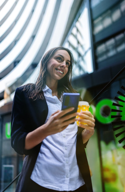 年轻的女商人在街上用她的智能手机图片下载