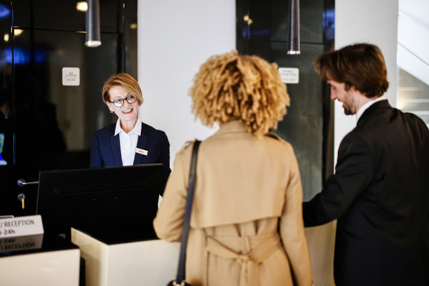 多民族商务夫妇离开酒店，在酒店前台办理退房手续图片下载