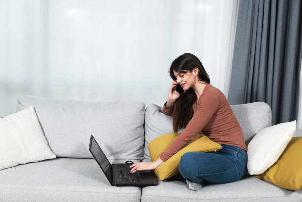 年轻的商人或女大学生坐在家里，用手机给IT部门或客户服务部门打电话，报告她的旧笔记本电脑出了问题。女沟通房地产经纪人谈论公寓租金图片下载