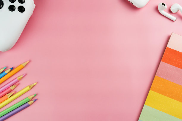 回到学校。粉红色背景的学校用品。儿童彩色配件，如蜡笔，笔记本，剪刀，视频游戏控制器。空间的文本。俯视图图片下载