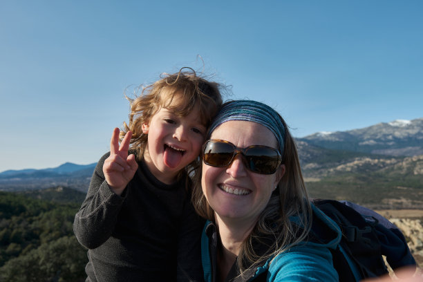 一对母子在大自然中自拍，小男孩做着鬼脸，露出舌头。图片下载