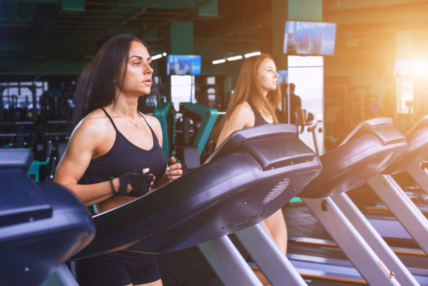 两名有吸引力的女运动员在跑道上的侧视图。女孩在跑步机上图片下载