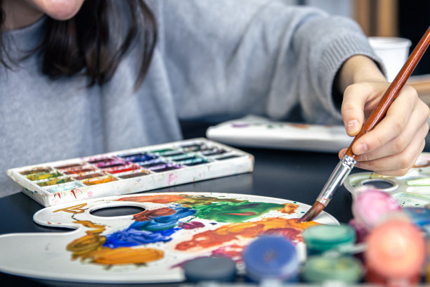 一位时髦的年轻女子在家里用颜料画画。图片下载