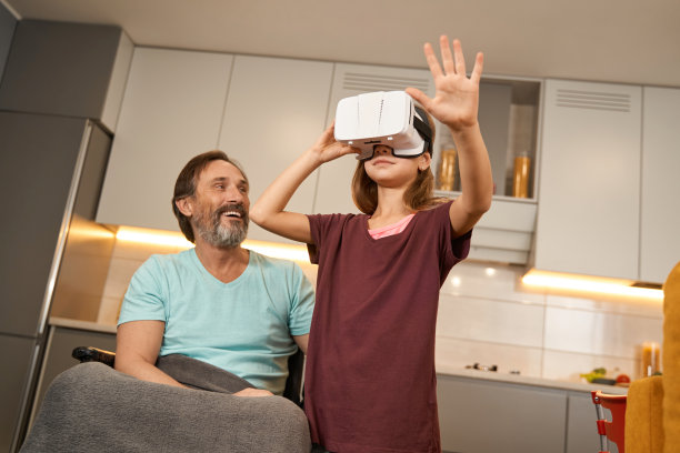 戴着虚拟现实眼镜的女孩站在一个坐轮椅的男人旁边图片下载