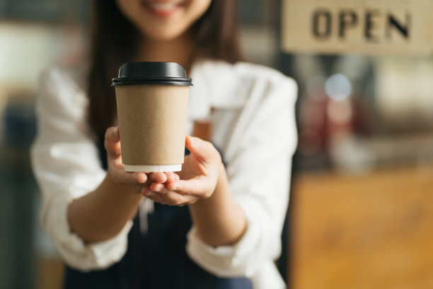 在咖啡馆里，一名女服务员端着两杯热咖啡。图片下载