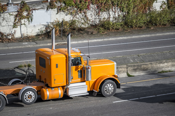 橙色经典时尚的大型钻机半挂车与扩展框架运输货物行驶在分开的高速公路上图片下载