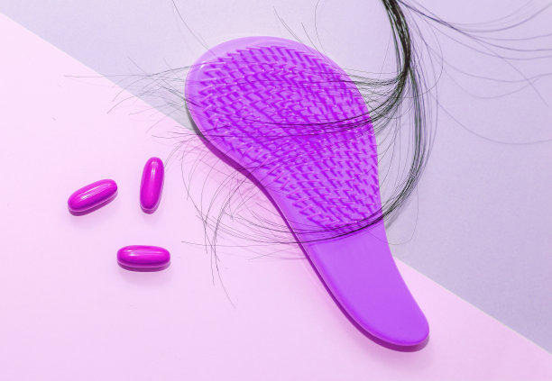 木制背景的塑料梳子，有掉落的头发和药丸图片下载