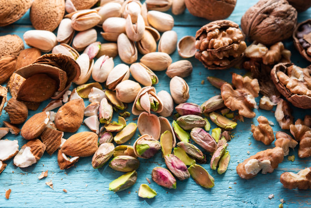 一堆干果，有机的，刚收获的开心果，杏仁，核桃，放在市场的木头上。图片下载