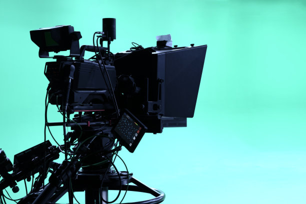 摄像机放在三脚架上，led泛光灯，提示器和绿色背景的显示器。色度键。绿屏图片下载