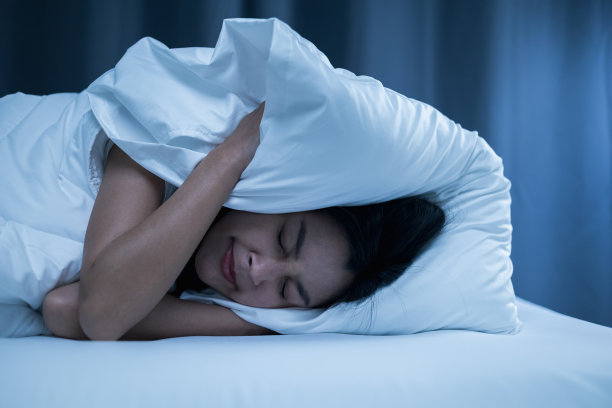 因为房子的一侧发出很大的噪音，干扰了她的睡眠，所以脸朝下躺下，用枕头盖住她的头。她晚上睡不着。图片下载