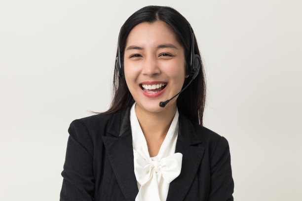 快乐年轻的亚洲商业女性呼叫中心。欢迎女接线员戴上耳机站在孤立的白色背景上。图片下载