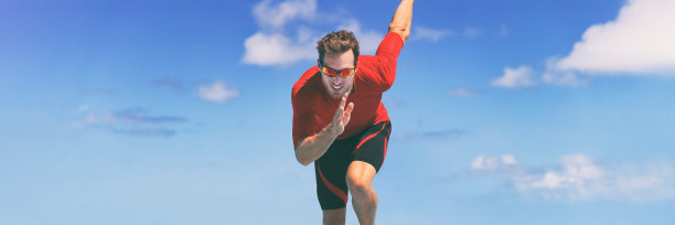 运动员赛跑运动员在跑步比赛中冲刺。水平横幅全景作物在蓝天背景。图片下载