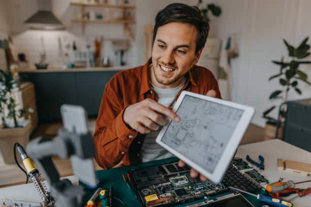 男人在家里一边用数码平板电脑一边用手机拍视频图片下载
