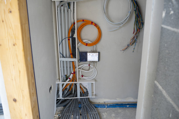 身穿蓝色牛仔裤衬衫的男性电工在建筑工地工作图片下载