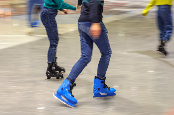 人们在冰场上滑冰。一对情侣手牵着手。运动模糊图片下载