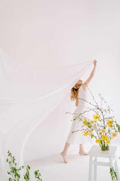 在装饰了鲜花的房间里拉窗帘的女人图片下载