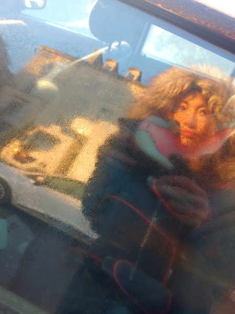 在寒冷的冬天，一个女人在车窗里用智能手机拍照，这张照片是透明的图片下载