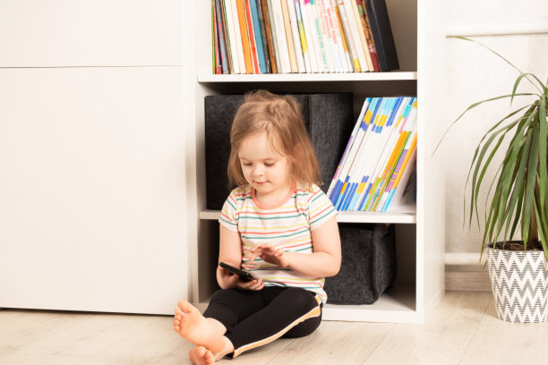 小女孩坐在房间里看着电话图片下载