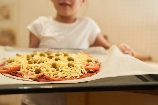 女孩手持烤盘，准备用牛肉烤披萨。烹饪图片下载
