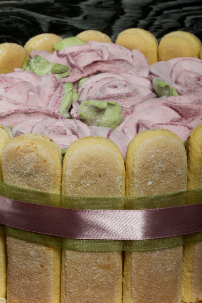 蛋糕配萨瓦蒂饼干和棉花糖玫瑰。系着丝带。丝带被系成一个蝴蝶结。图片下载