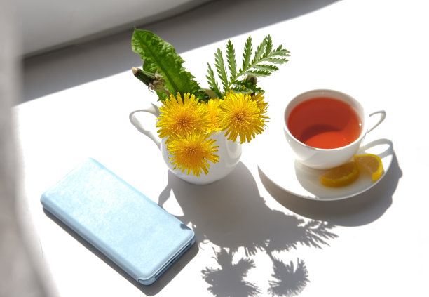 一杯茶，蒲公英花和电话。春天的早晨。图片下载