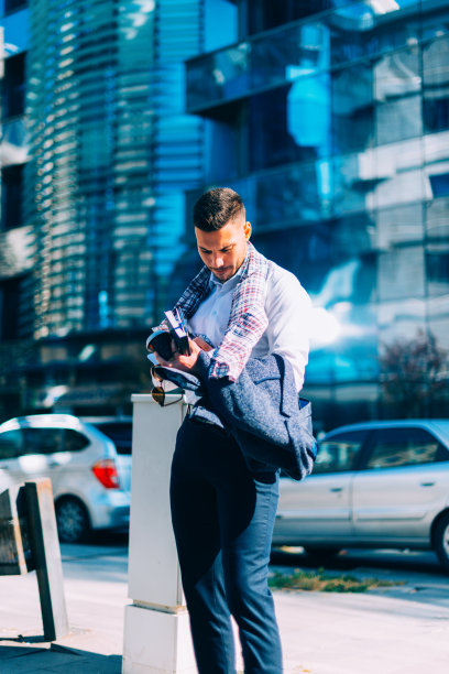 一个年轻的商人正走在市中心，手里拿着笔记本和咖啡，环顾四周图片下载