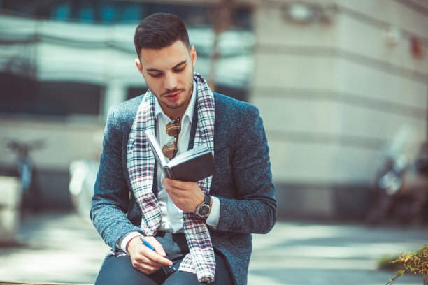 英俊的男人坐在户外，看书图片下载