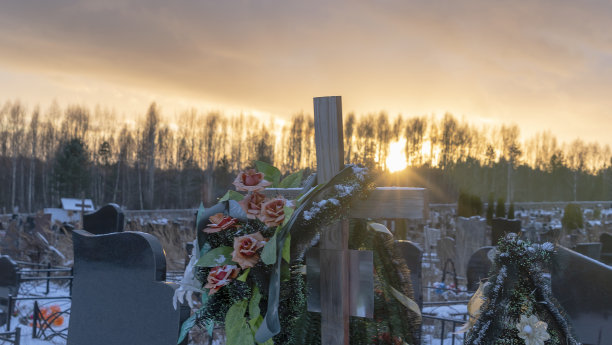 日落时分带有假花的木制坟墓十字架，白雪皑皑的冬季东正教传统墓地图片下载