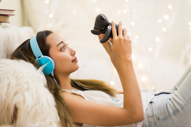 年轻女子一边玩泰迪熊一边听音乐图片下载