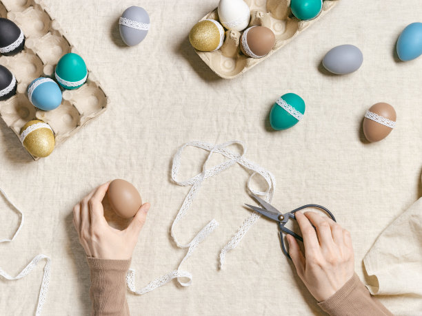 装饰彩色复活节彩蛋，准备快乐的复活节庆祝活动，妇女装饰染色鸡蛋用胶带花边桌布上的生活方式美感照片在家里，diy节日图片下载