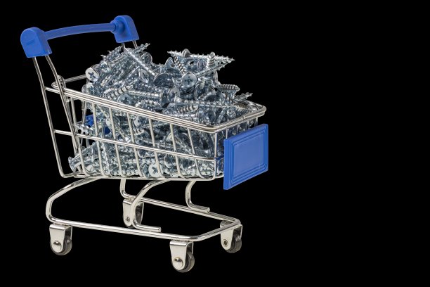 近距离观察玩具购物手推车装满螺丝，孤立，在黑色背景上。图片下载